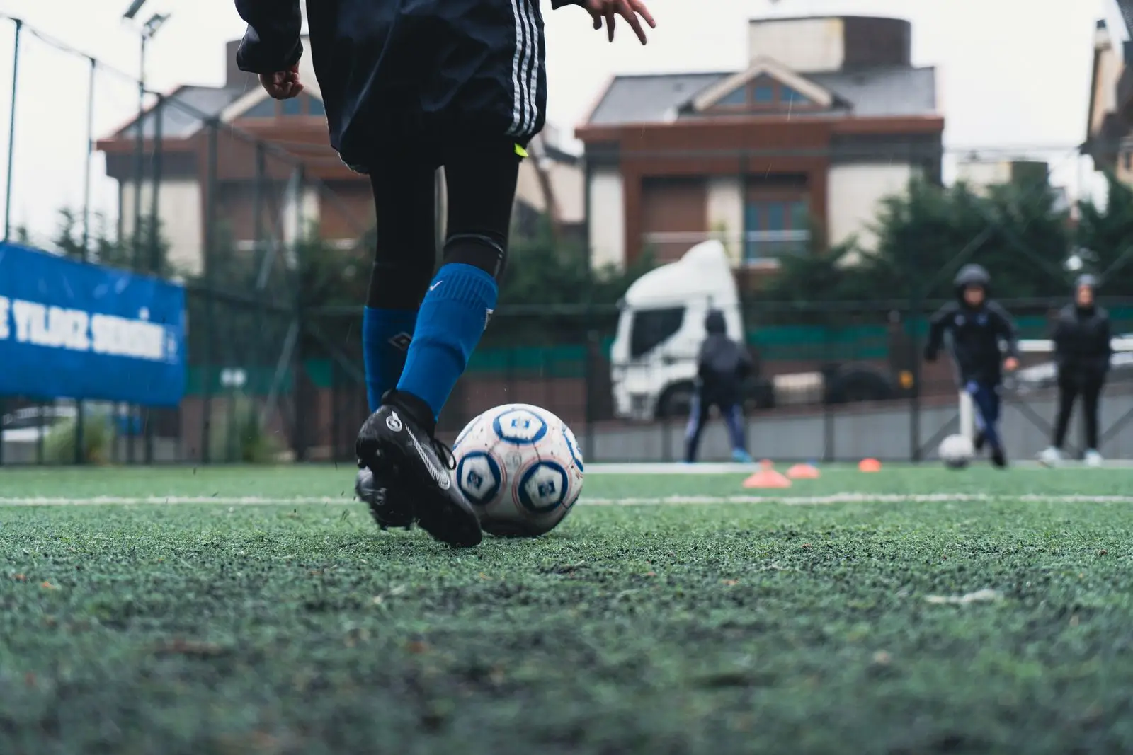 Close-up of a young player's feet dribbling a football through training cones