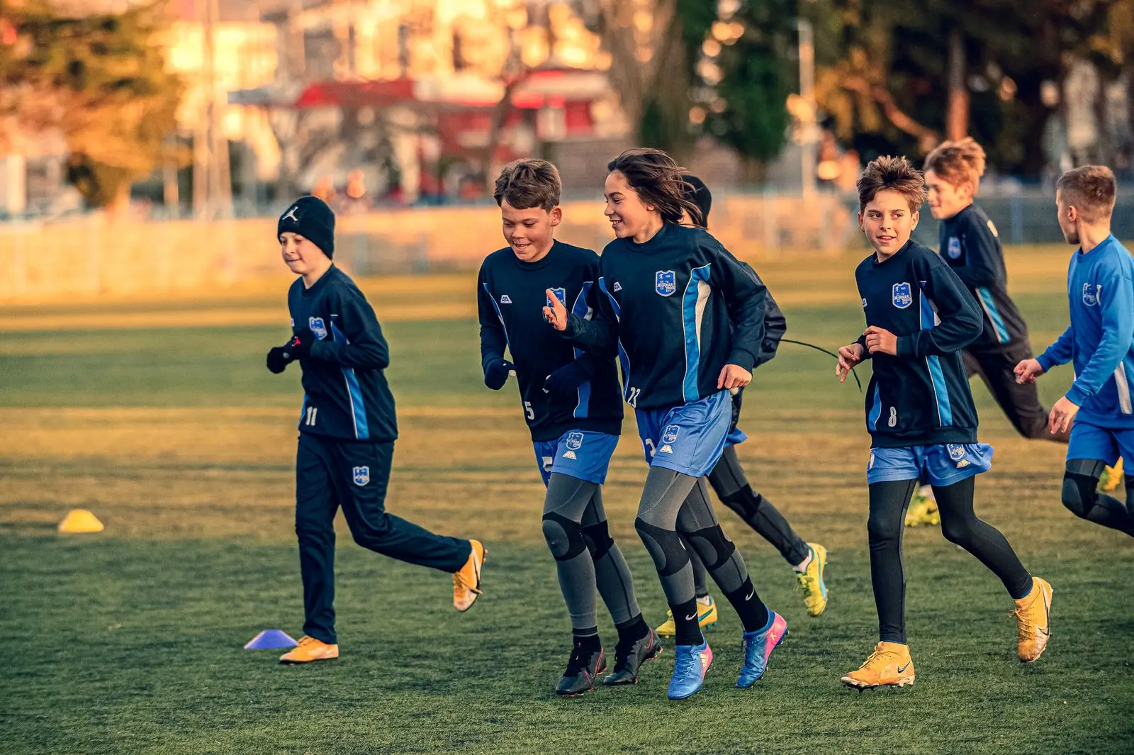 Young players sprinting across an outdoor pitch at golden hour
